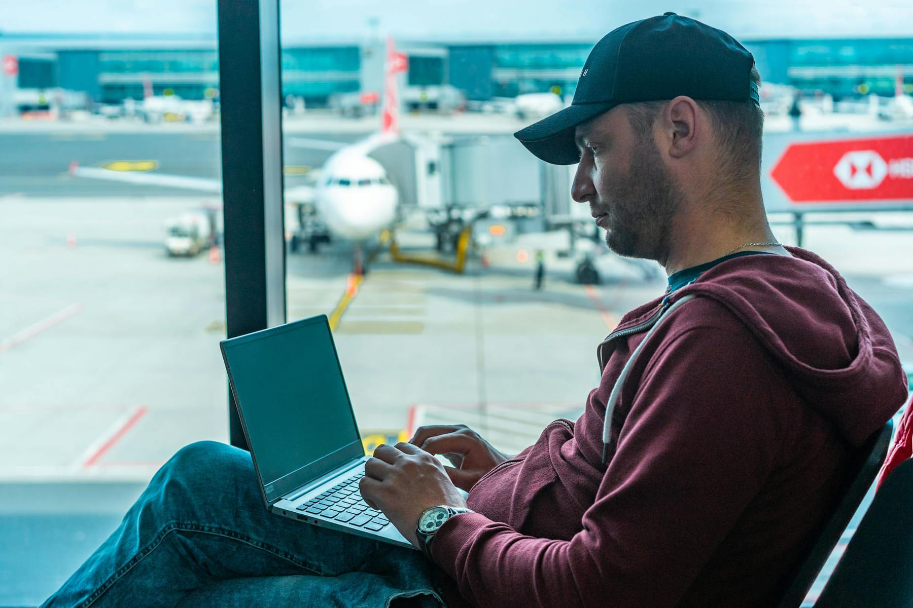 A man working on his laptop in an airport terminal, with a plane visible outside. on Points and Pathways