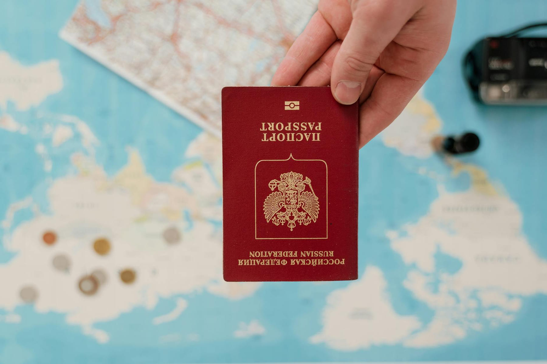A hand holding a Russian passport over a map, suggesting travel preparation. on Points and Pathways