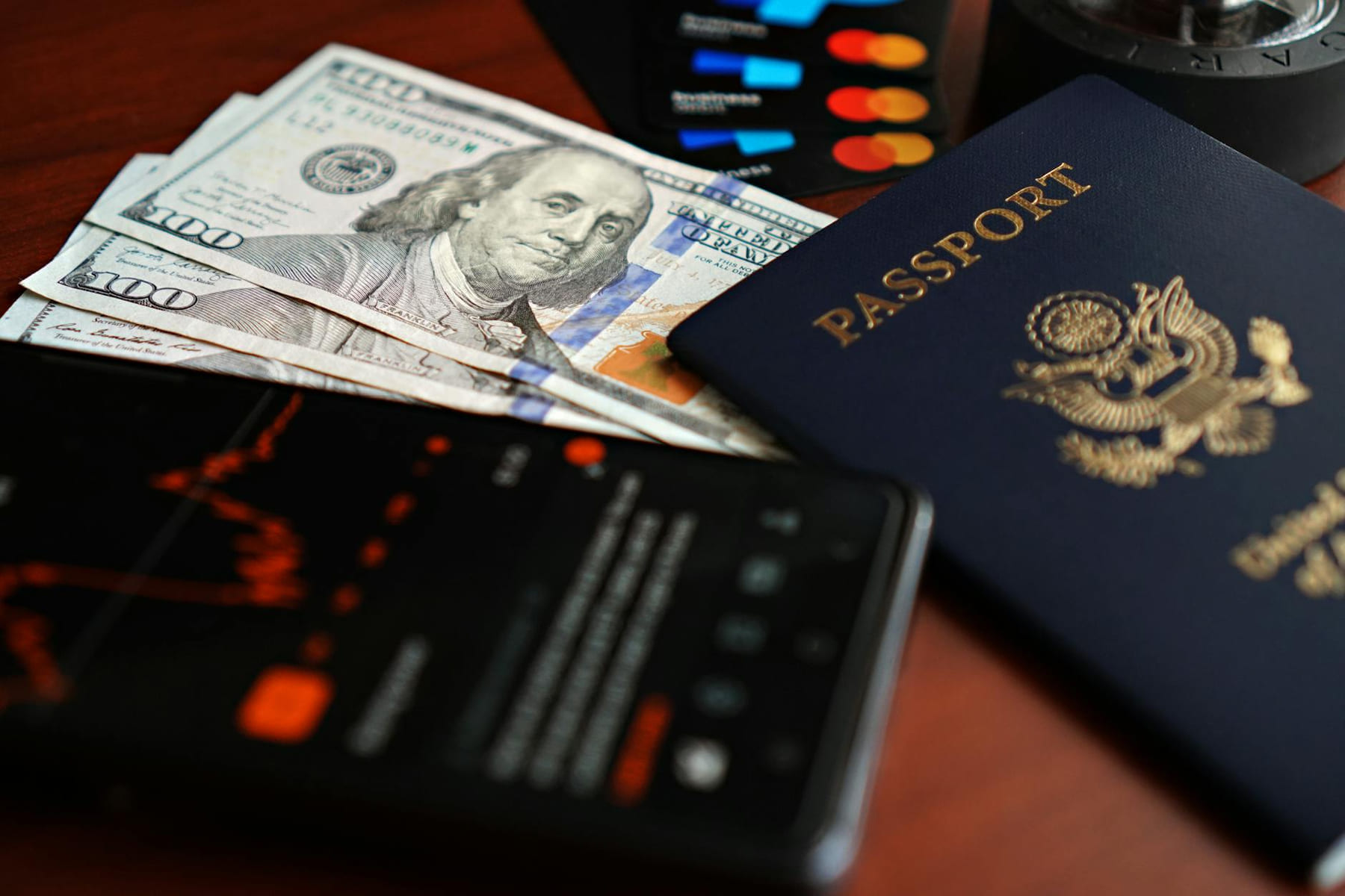 A flat lay of travel essentials including a passport, US currency, and credit cards on a table. on Points and Pathways