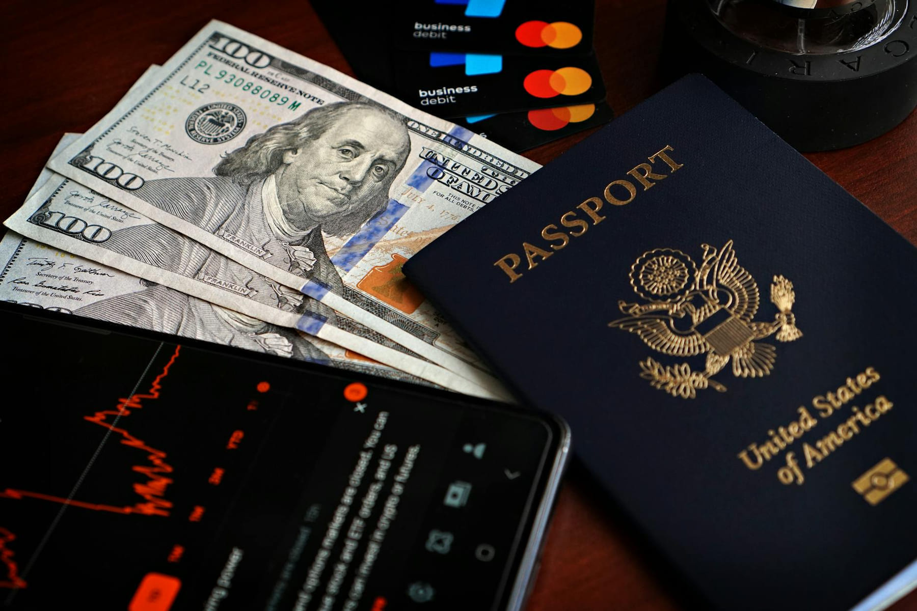 US passport with hundred-dollar bills, credit cards and smartphone showing stock data. on Points and Pathways