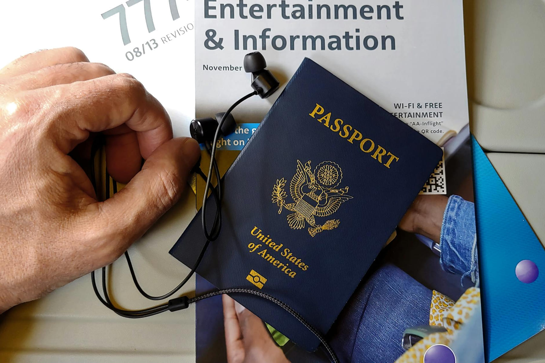 Close-up of US passport with inflight magazine and headphones on an airplane seat, ready for travel. on Points and Pathways
