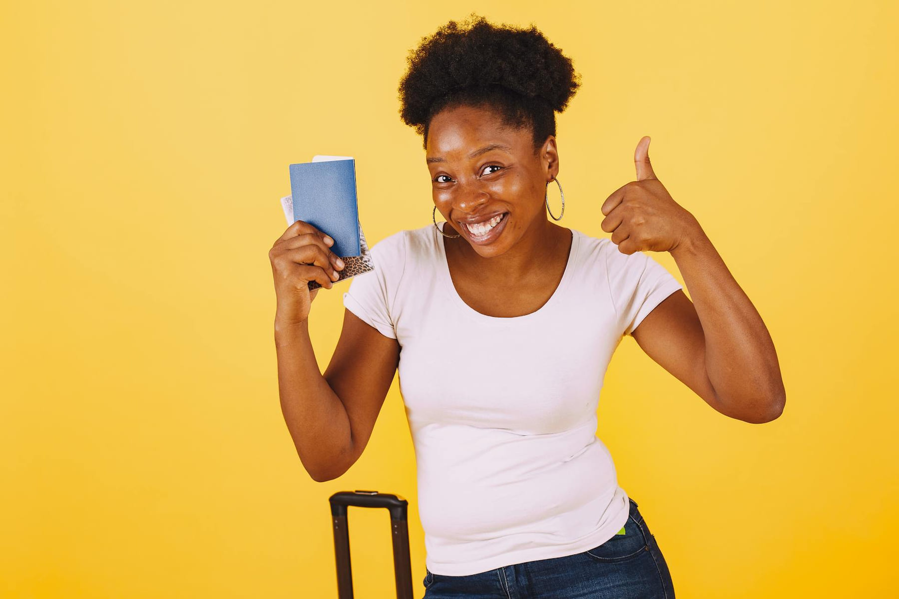 Smiling woman holding passport giving thumbs up against yellow background. on Points and Pathways