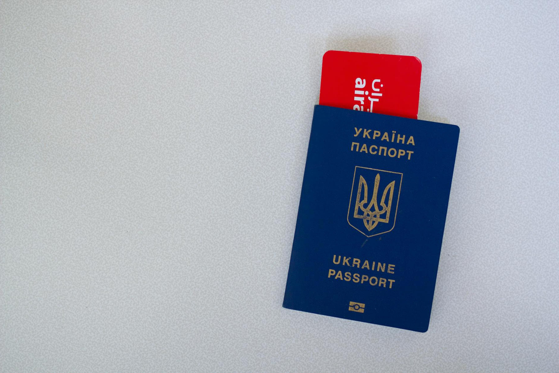 Close-up of a Ukrainian passport with an airline boarding pass on a white surface. on Points and Pathways