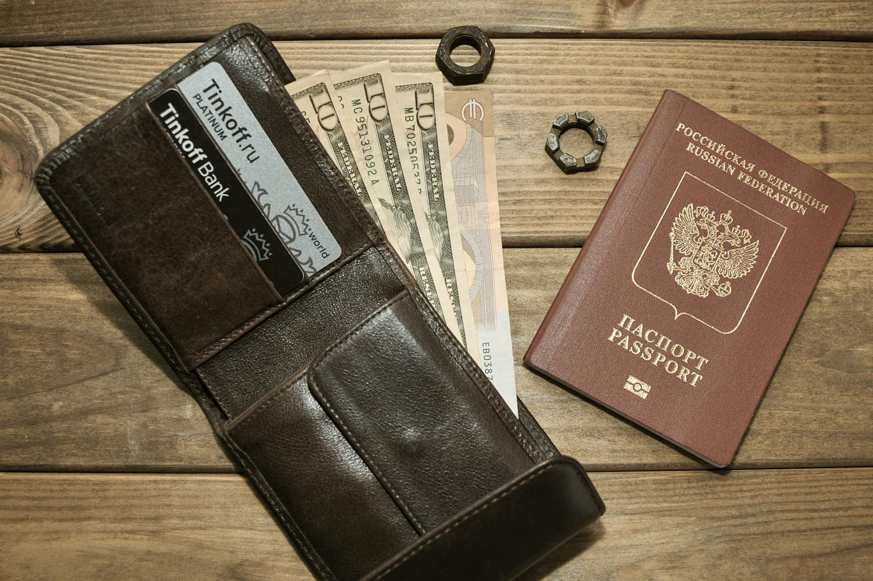 Brown leather wallet with cards, assorted currencies, and passport on wood surface. on Points and Pathways