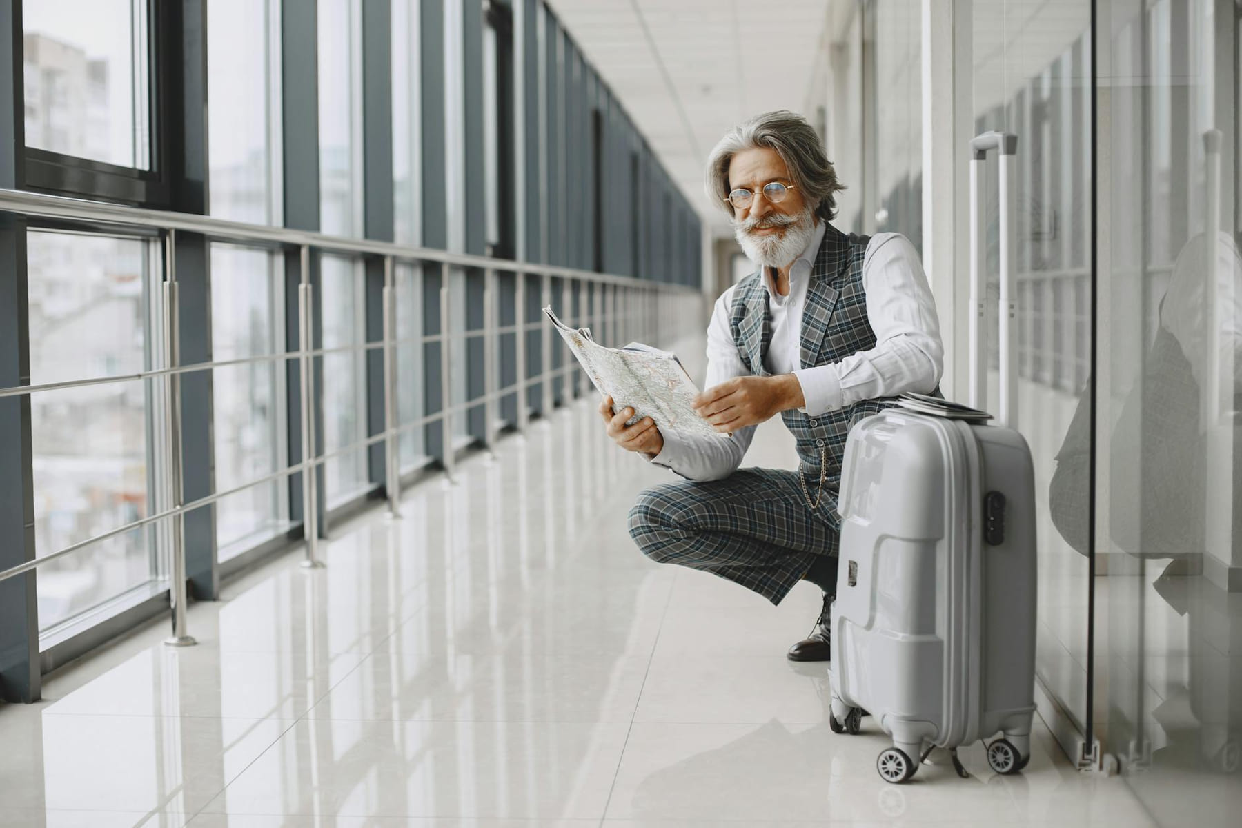 Senior man in airport hallway holding a map, sitting beside luggage, illustrating travel and exploration. on Points and Pathways